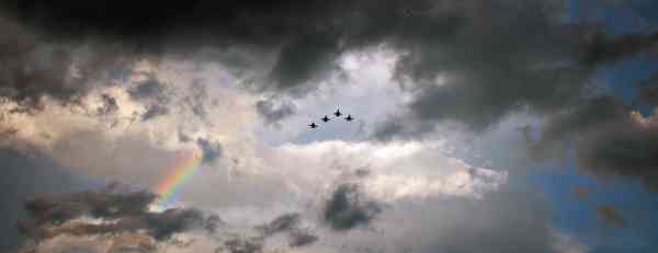 A skyward photo of clouds, a rainbow, and jets flying by during a July 4 Independence Day celebration