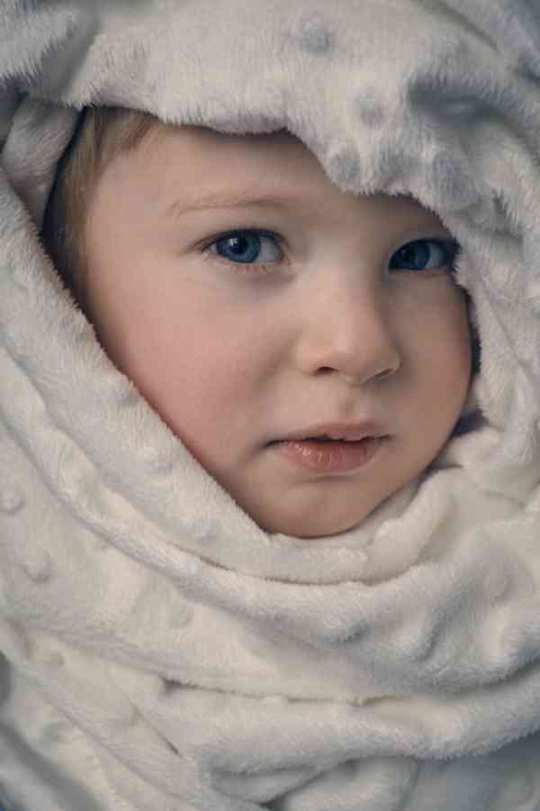 A portrait of a child, swaddled in a blanket