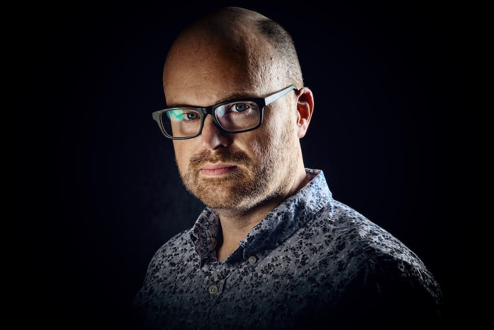 A profile picture of David Hepworth, the author of this blog. He is looking at the camera with a solemn expression and is wearing a short-sleeved button-up shirt and thick black plastic glasses.